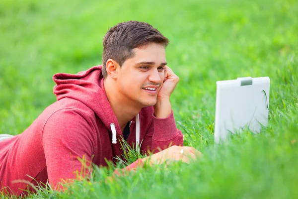 Student met laptop op groen gras — Stockfoto