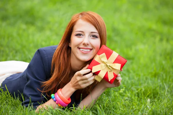 Wanita berambut merah wtih hadiah di rumput hijau . — Stok Foto