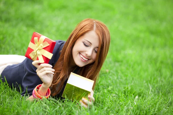 Redhead women wtih gift at green grass. — Stock Photo, Image