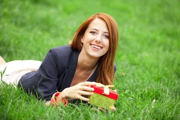 Redhead women wtih gift at green grass. — Stock Photo, Image