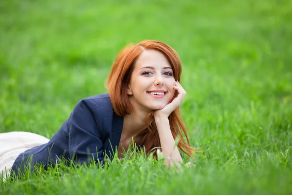 Yeşil çimlere yatan kızıl saçlı kadın — Stok fotoğraf