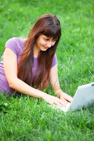 Menina morena na grama verde com notebook — Fotografia de Stock