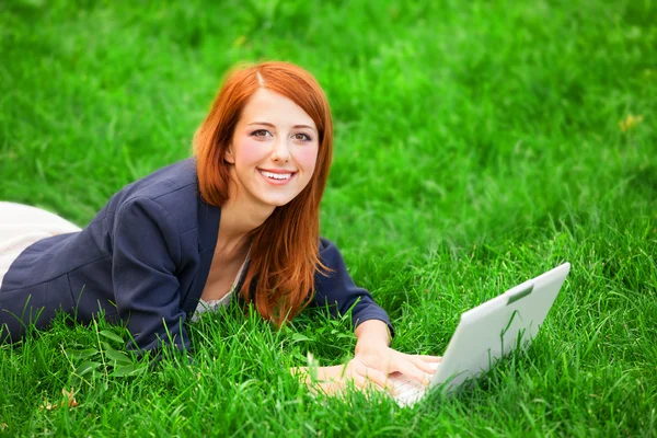 Ragazza rossa a erba verde con notebook — Foto Stock