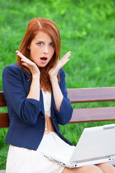 Redhead girl sitting at the bench with notebook — Stock Photo, Image