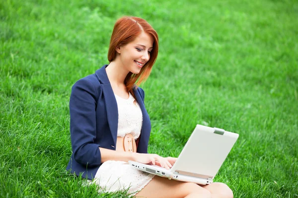 Rusovláska dívka na zelené trávě s notebookem — Stock fotografie