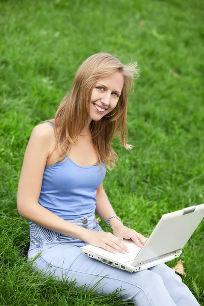 Menina loira na grama verde com notebook — Fotografia de Stock