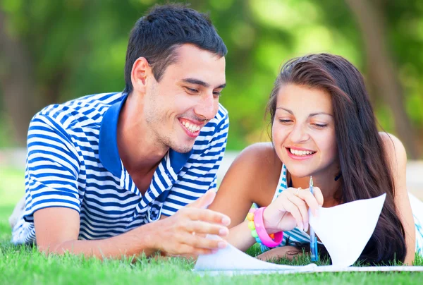 Young students sitting on green grass with note book. — Stock Photo, Image