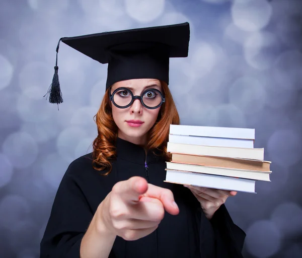 Abschlussschülerin im akademischen Kleid mit Büchern — Stockfoto