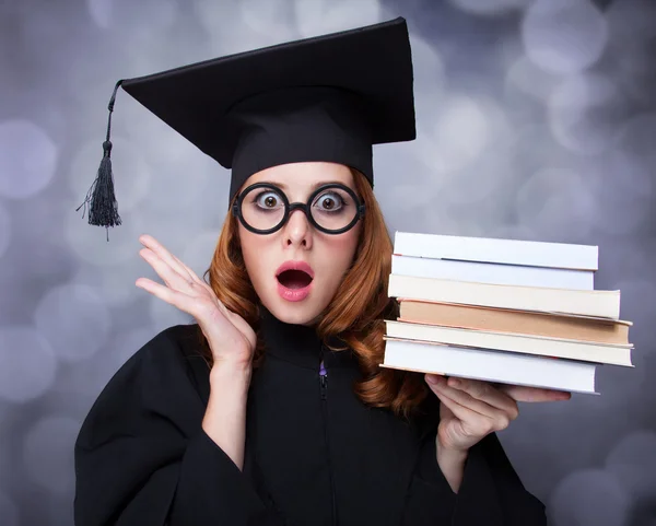 Abschlussschülerin im akademischen Kleid mit Büchern — Stockfoto