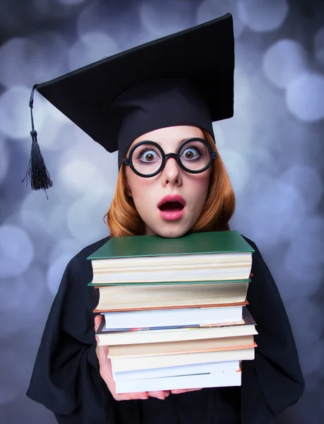 Abschlussschülerin im akademischen Kleid mit Büchern — Stockfoto