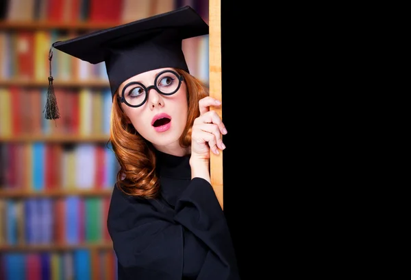 Graduating student girl in an academic gown near blackboard — Stock Photo, Image