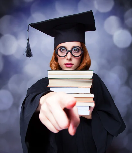 Abschlussschülerin im akademischen Kleid mit Büchern — Stockfoto
