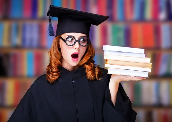 Выпускница в академическом платье с книгами — стоковое фото