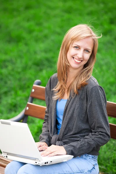 Girl sitting at the bench with notebook — Stock Photo, Image