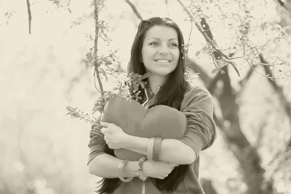 Beautiful girl with toy heart in spring park — Stock Photo, Image