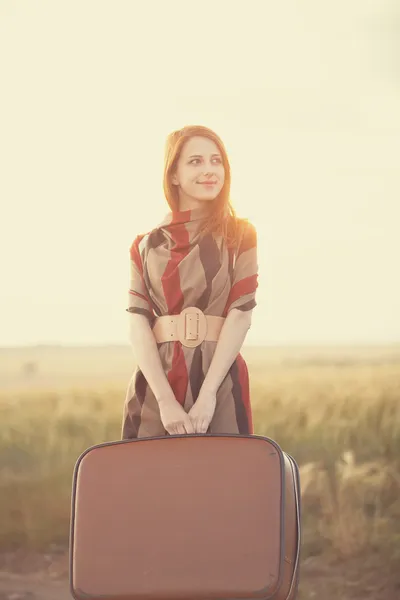 Rödhårig tjej med resväska på utomhus. — Stockfoto
