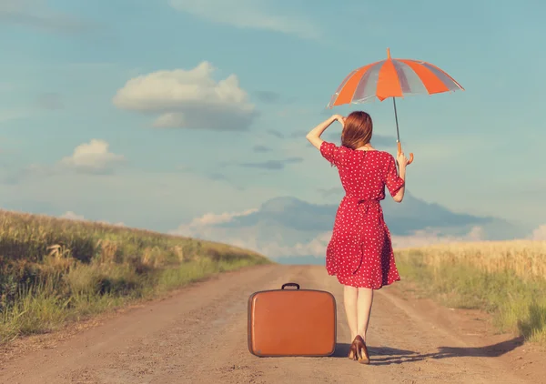 Ragazza rossa con ombrello e valigia all'aperto — Foto Stock