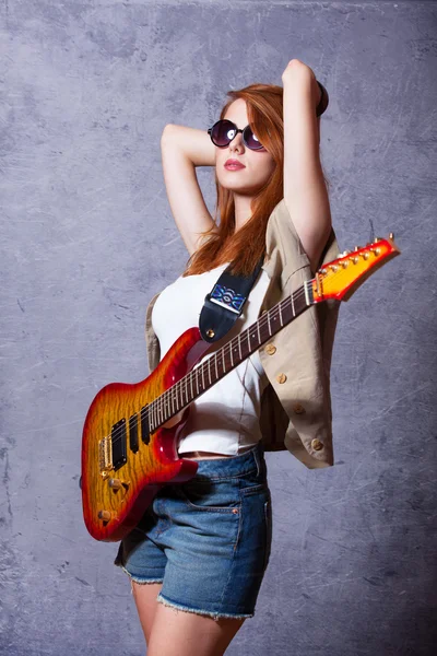 ギターの壁の近くで赤毛の女の子 — ストック写真