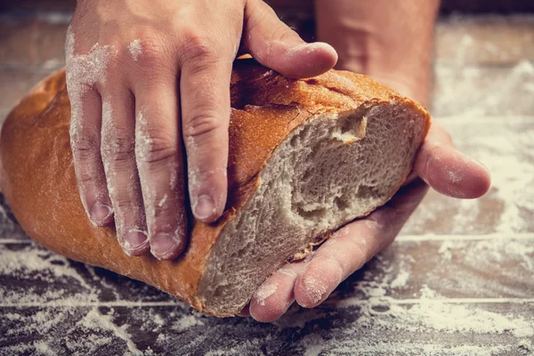 Baker's hands with a bread. Photo with high contrast — Stock Photo, Image