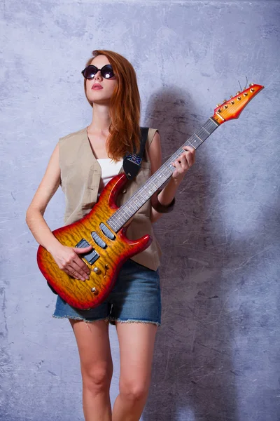 Fille rousse avec guitare près du mur — Photo