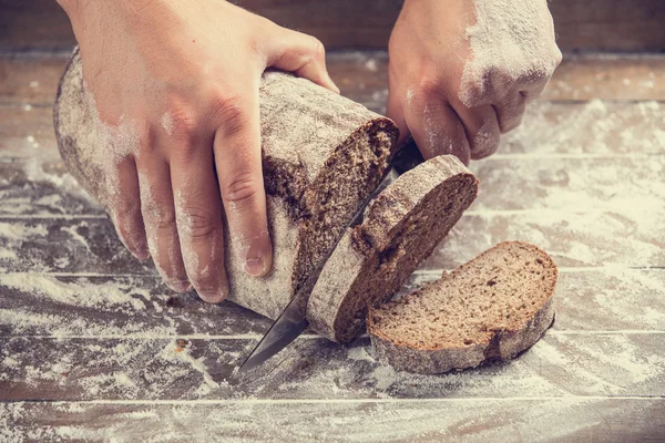 Mężczyzna ręce kroi chleb domowej roboty — Zdjęcie stockowe