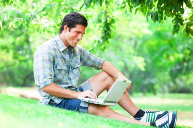 Yeşil çimlerde dizüstü bilgisayarı olan öğrenci