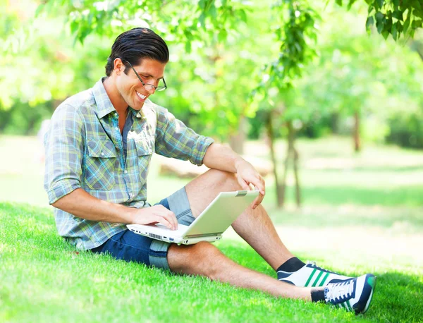 Student met laptop op groen gras — Stockfoto