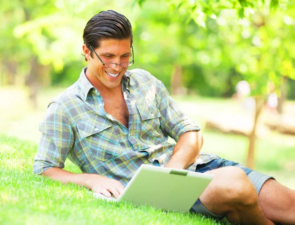 Studerande med bärbar dator vid grönt gräs — Stockfoto