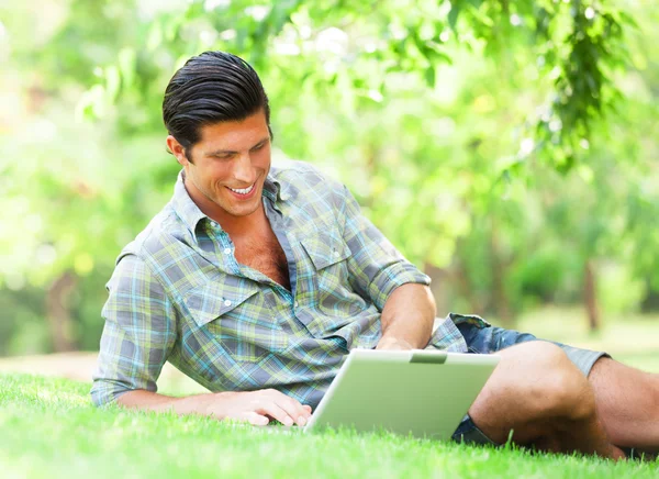 Студент с ноутбуком на зеленой траве — стоковое фото