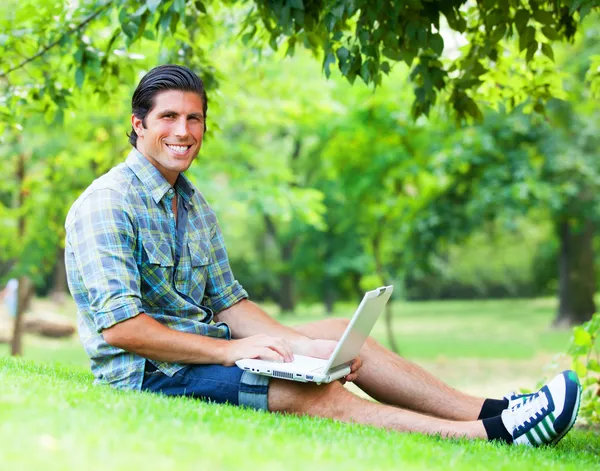 Студент з ноутбуком на зеленій траві — стокове фото