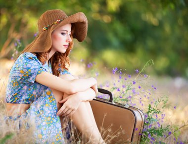 Kızıl saçlı kız sonbahar çimlere oturup çanta