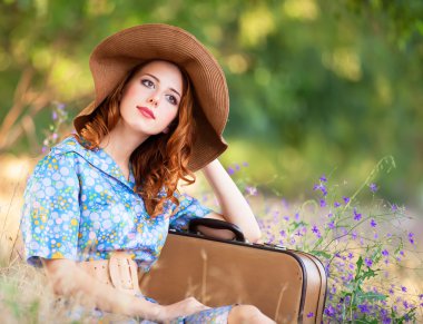 Kızıl saçlı kız sonbahar çimlere oturup çanta