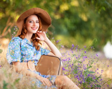 Kızıl saçlı kız sonbahar çimlere oturup çanta