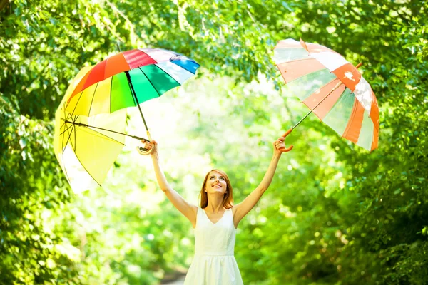 Рыжая девушка с тремя зонтиками на открытом воздухе — стоковое фото