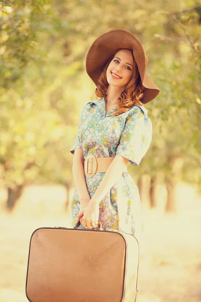 Redhead girl with suitcase at tree's alley. — Stock Photo, Image