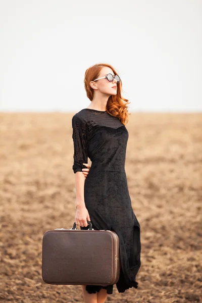 Redhead girl with suitcase at autumn field — Stock Photo, Image