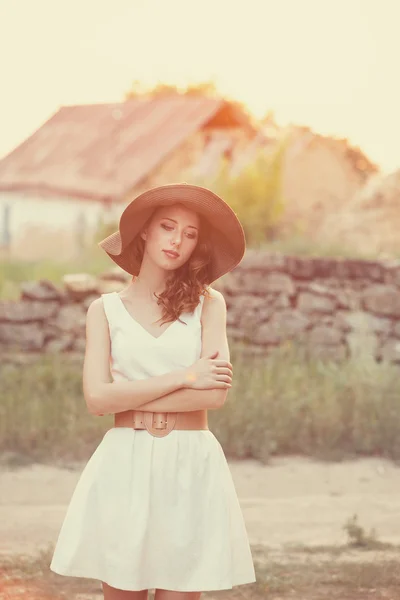 Ragazza rossa all'aperto. Vecchia casa di campagna sullo sfondo . — Foto Stock