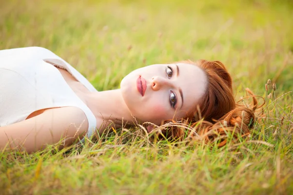 Ruiva menina deitada na grama — Fotografia de Stock