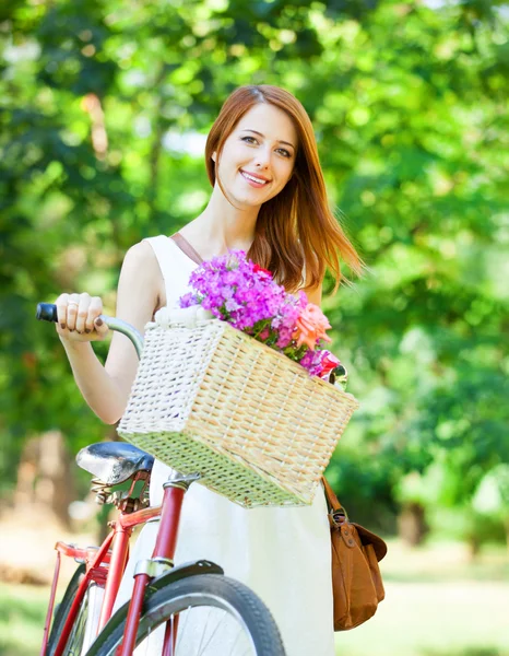 Ragazza rossa con bici retrò nel parco . — Foto Stock