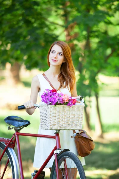 Ragazza rossa con bici retrò nel parco . — Foto Stock