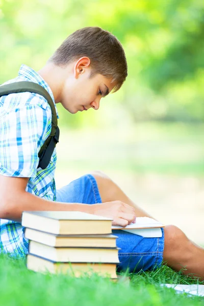 Tiener jongen met boeken en laptop buiten. — Stockfoto