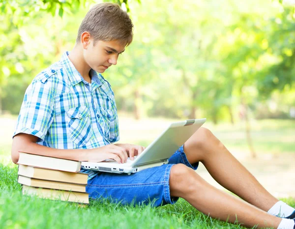 Teen boy with books and laptop in the park. — Stock Photo, Image