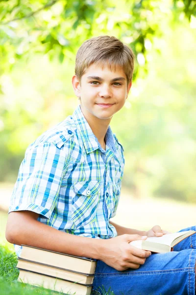 Teen pojke med böcker och anteckningsbok i parken. — Stockfoto