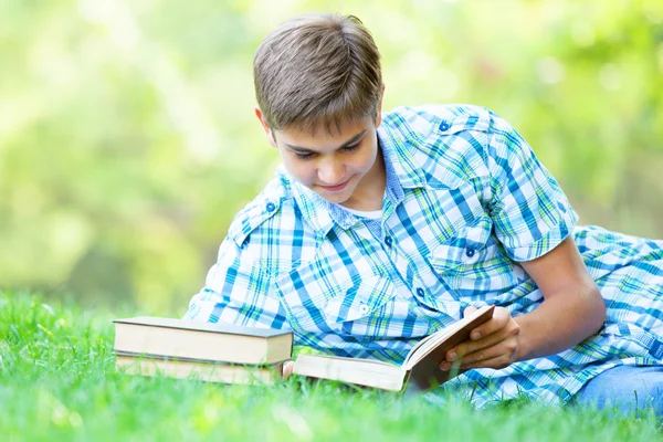 Tiener jongen met boeken en notebook in het park. — Stockfoto