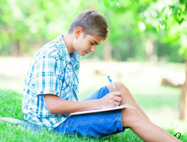 Хлопчик-підліток з книгами і блокнотом в парку . — стокове фото