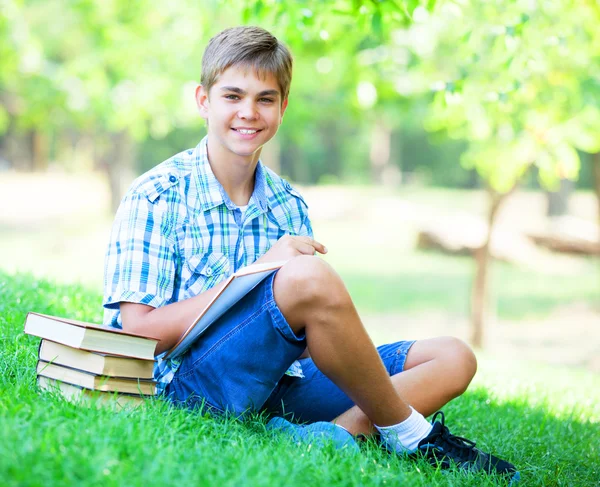 Jeune garçon avec des livres et un cahier dans le parc . — Photo