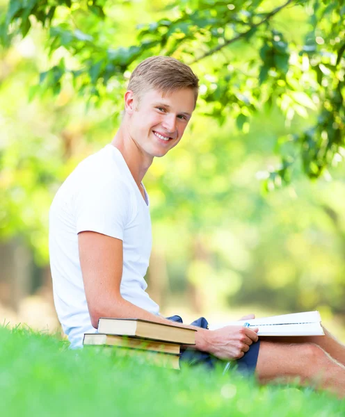 Teen pojke med böcker och anteckningsbok i parken. — Stockfoto