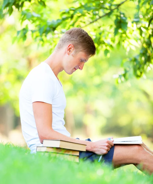 Хлопчик-підліток з книгами і блокнотом в парку . — стокове фото