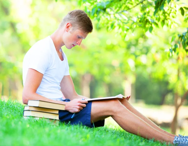 Teen boy with books and notebook in the park. — Stock Photo, Image