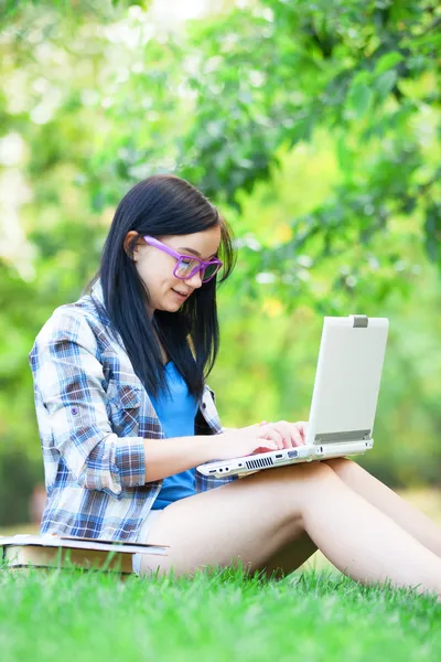 Tiener meisje met laptop in het park. — Stockfoto